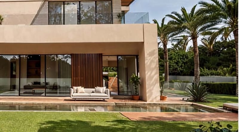 Photographie communiquée : façade d’une villa du programme, terrasse et bassin.